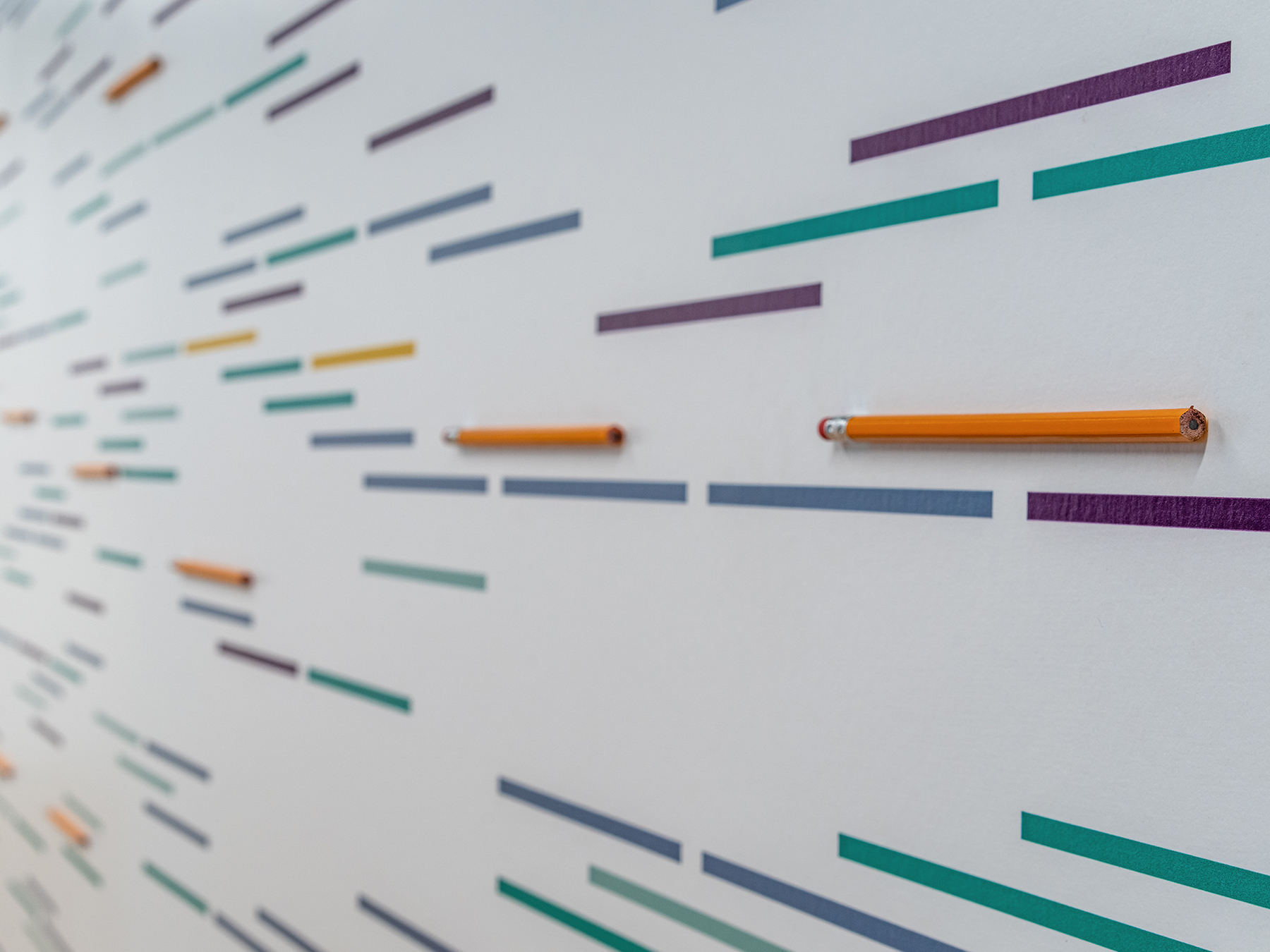 Detail photo of a wall graphic with colorful lines and dimensional pencils