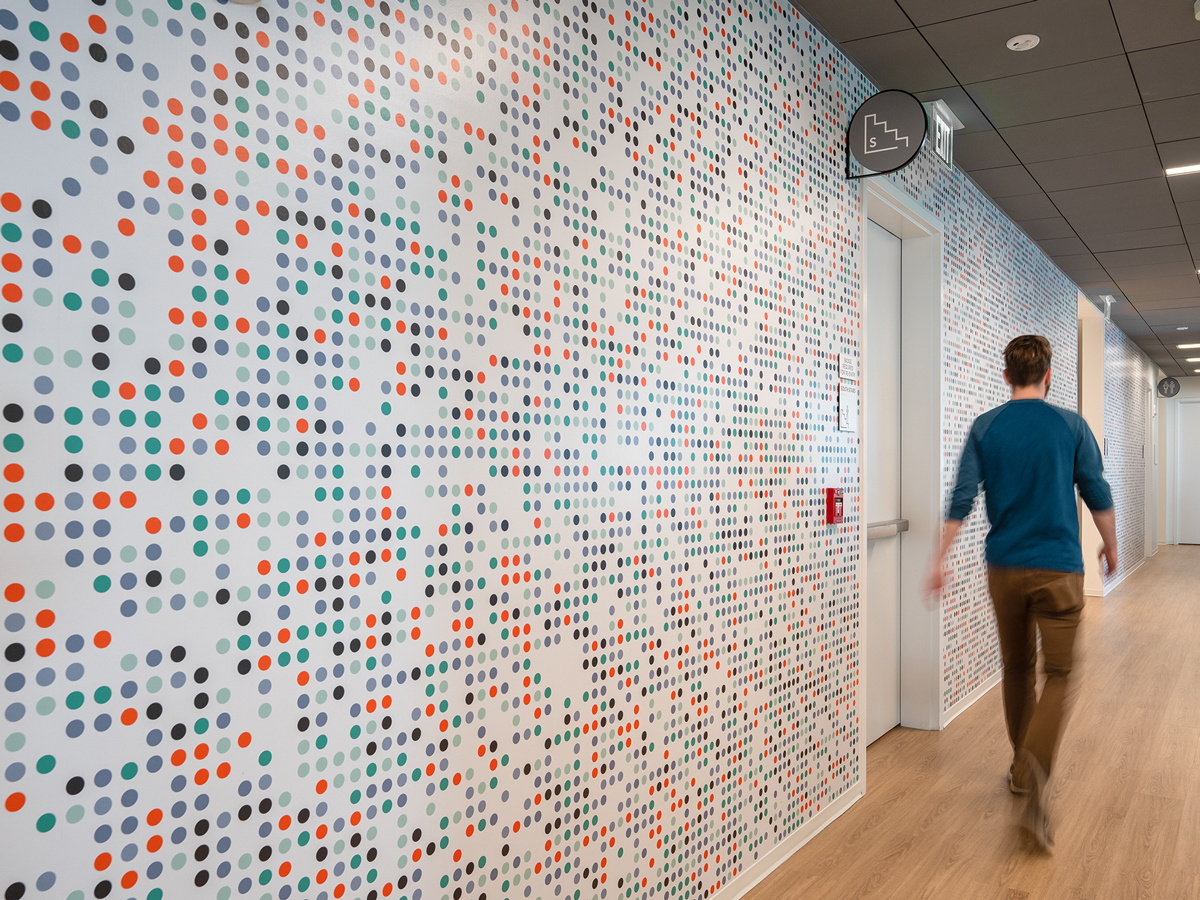 Person walking past a wall graphic with colorful circles and dimes