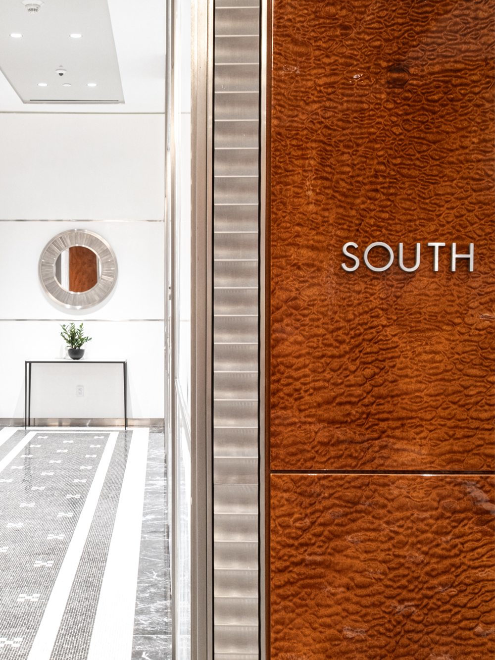 Detail shot of elevator lobby, focusing on metal signage that reads "SOUTH"