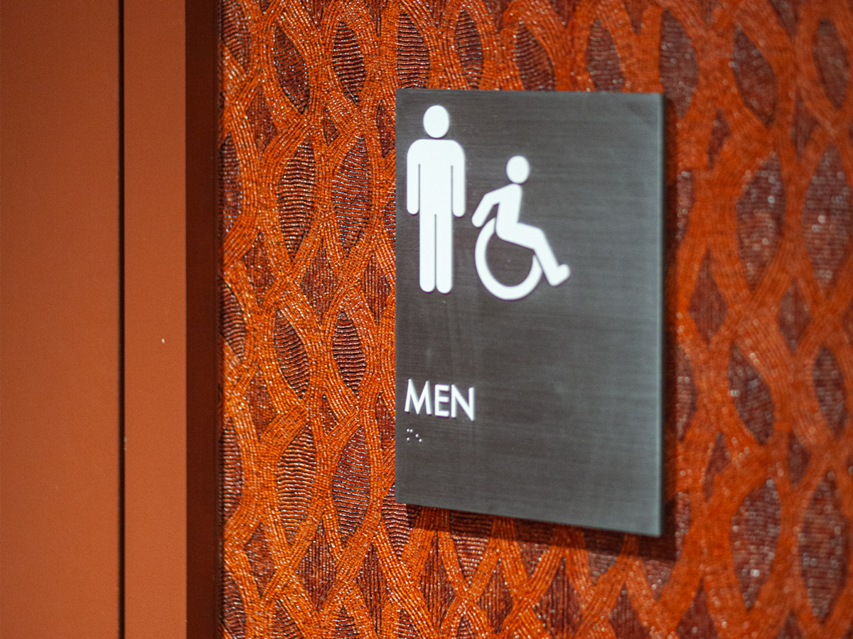 Detail photo of men's restroom sign on a red textured wallpaper